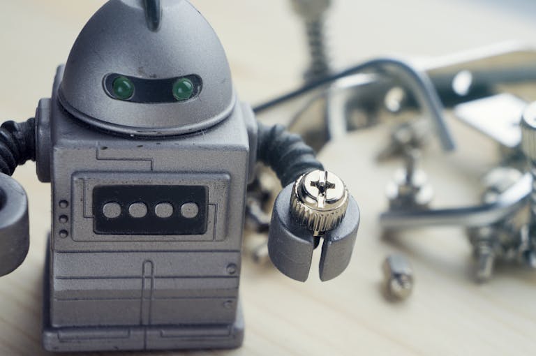 Detailed view of a toy robot holding a metallic screw, surrounded by tools.