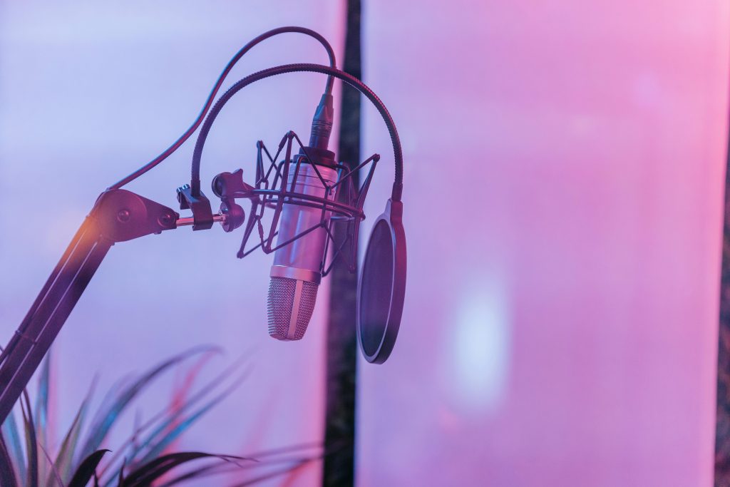 Generative AI, SEO & LLMO Tools Close-up of a condenser microphone with a pop filter in a vibrant studio setting.